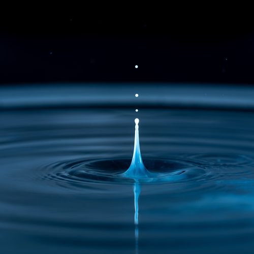 Water droplet suspended above ripples